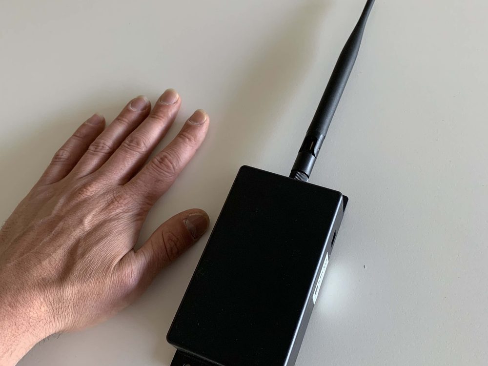 Een iotta-gateway met antenne naast een hand, die laat zien dat het apparaat ongeveer handpalmgroot is